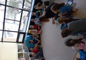 Dzieci z Panią Bibliotekarką siedzą w kole na dywanie. Rozmawiają o swoich talentach